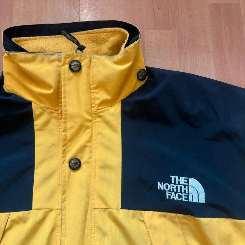 The North Face 2-in-1 jacket yellow black color block design with embroidered logos.