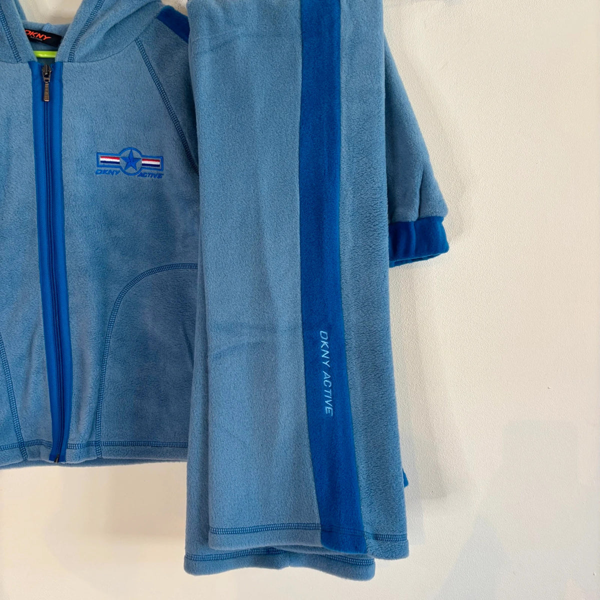 DKNY blue fleece tracksuit set with logo branding and side stripe details.