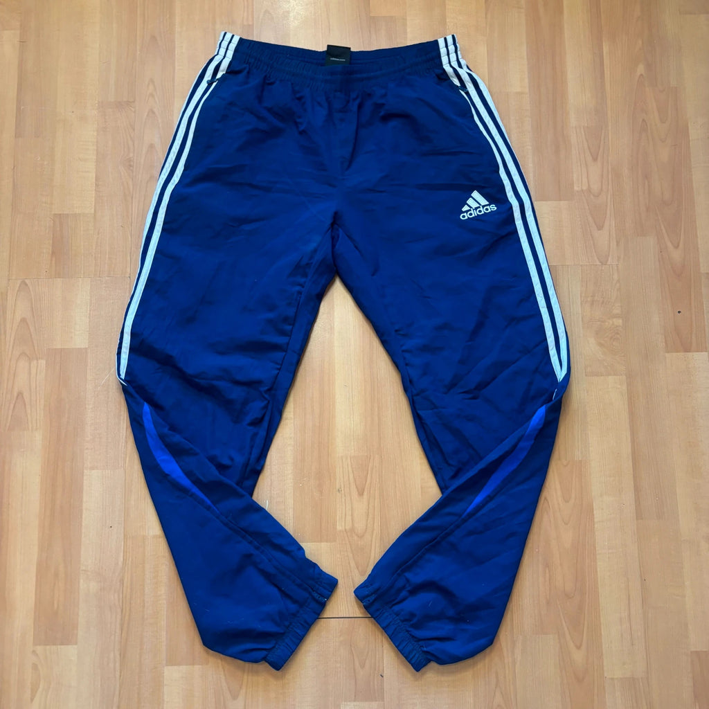 Adidas blue joggers with white three stripes, elastic waist, and ankle zips.