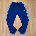 Adidas blue joggers with white three stripes, elastic waist, and ankle zips.