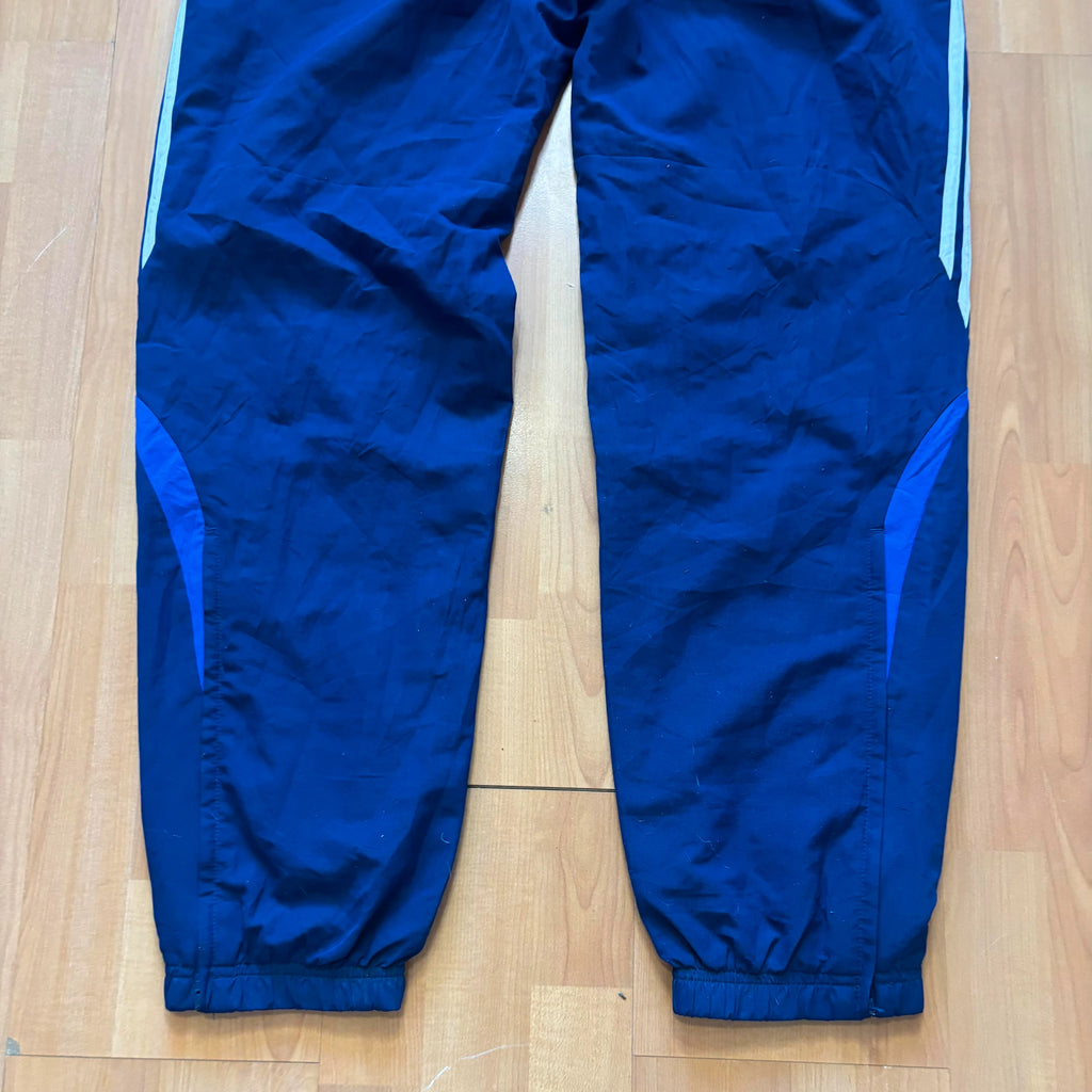 Adidas blue joggers with white three stripes, elastic waist, and ankle zips.