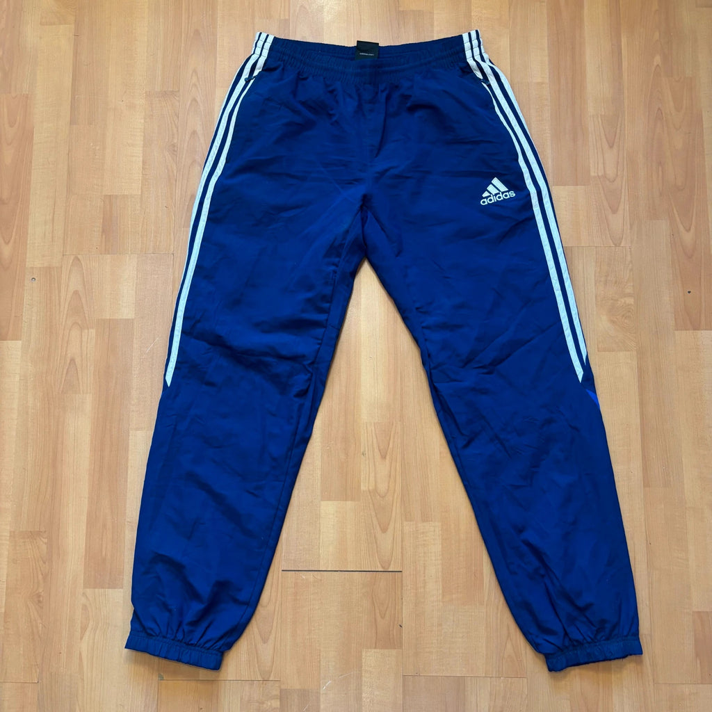 Adidas blue joggers with white three stripes, elastic waist, and ankle zips.