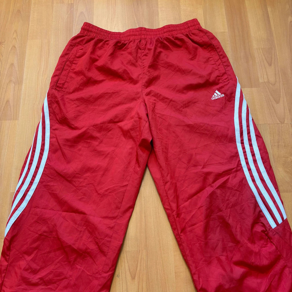 Adidas red joggers with white three-stripe detailing and adjustable drawstring waist.