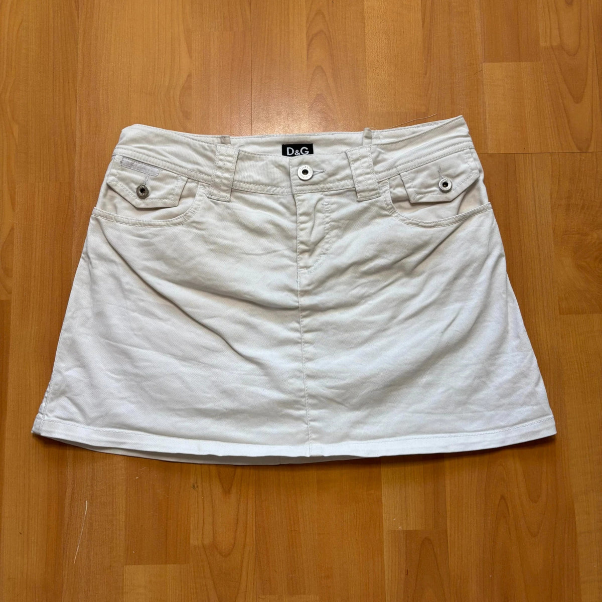 Dolce & Gabbana white denim mini skirt with utility pockets and branded hardware.