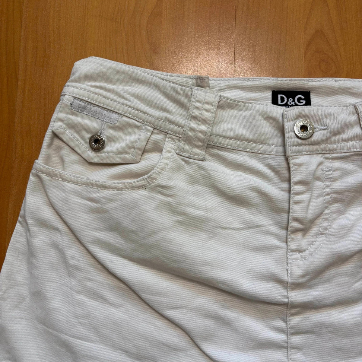 Dolce & Gabbana white denim mini skirt with utility pockets and branded hardware.