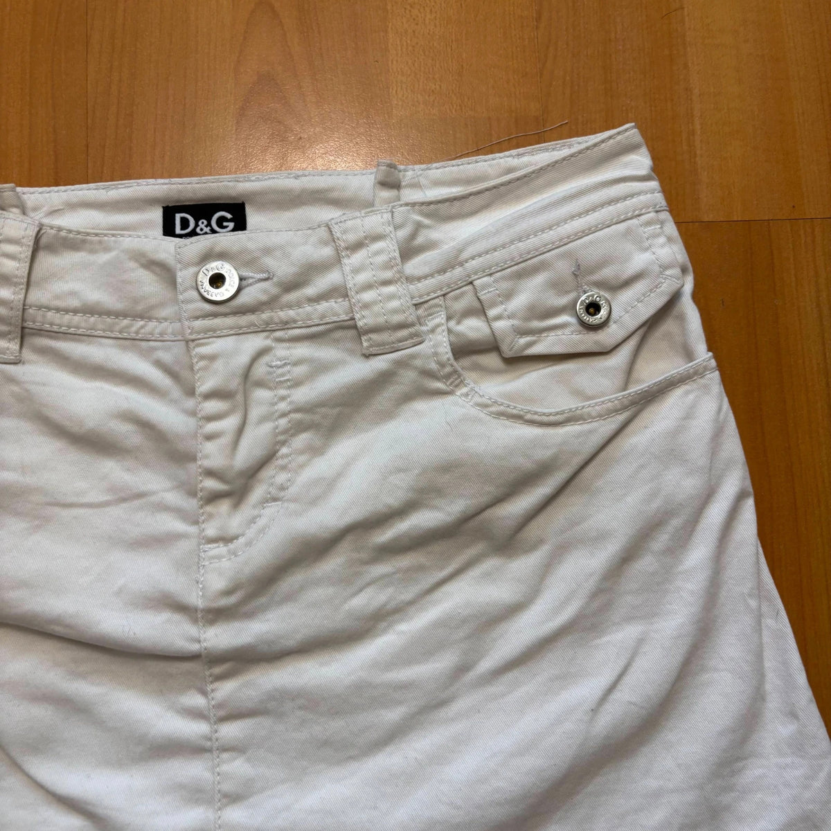 Dolce & Gabbana white denim mini skirt with utility pockets and branded hardware.