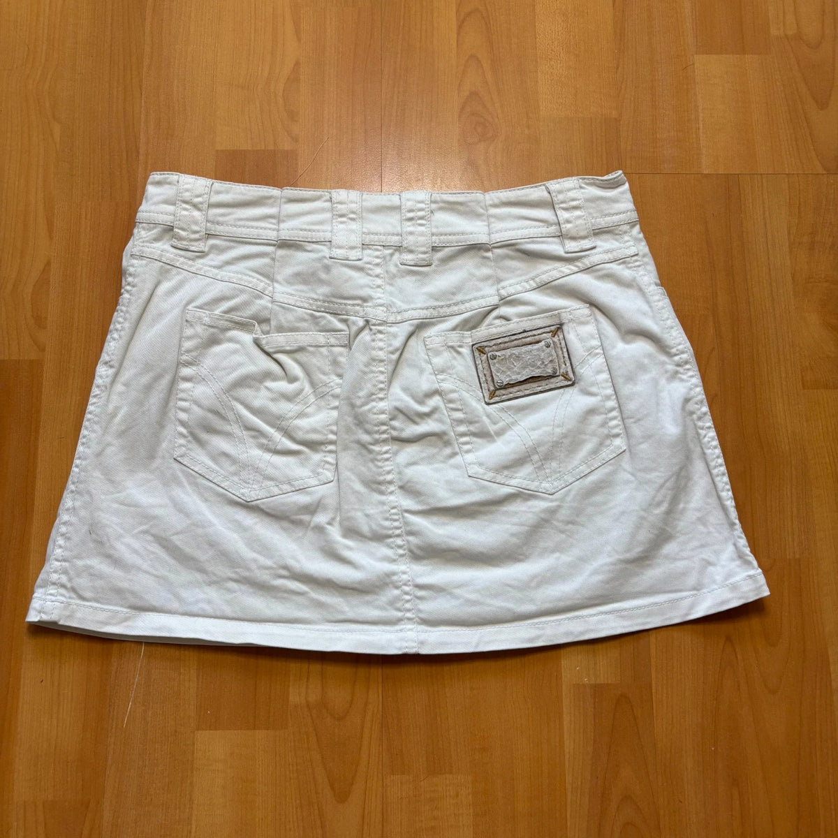 Dolce & Gabbana white denim mini skirt with utility pockets and branded hardware.