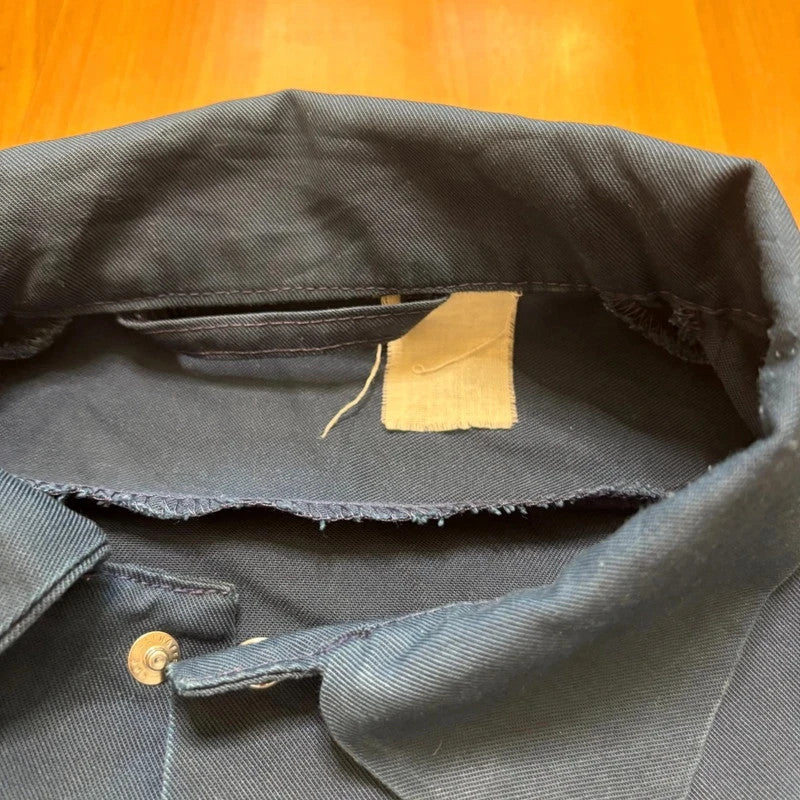 Vintage Dressing navy chore jacket with snap buttons, utility pockets, and patch repair detail.