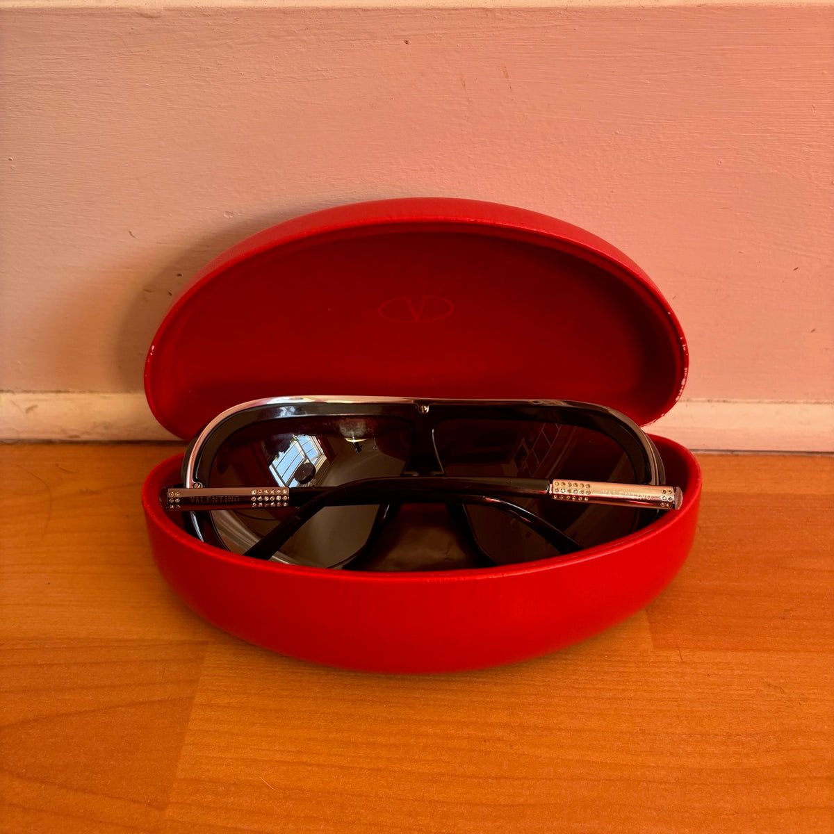 Valentino black sunglasses with rhinestone detailing and red hard case featuring logo.