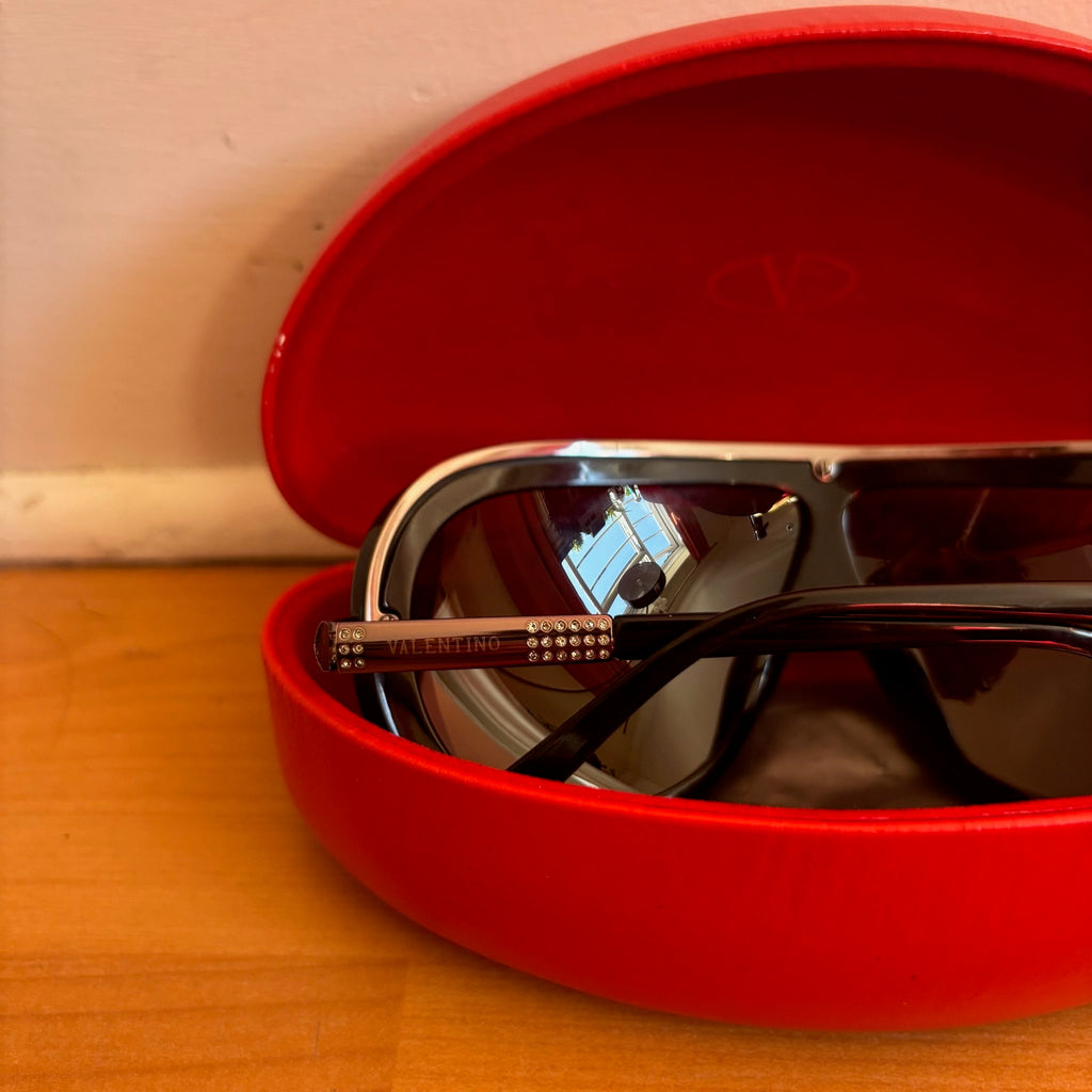 Valentino black sunglasses with rhinestone detailing and red hard case featuring logo.
