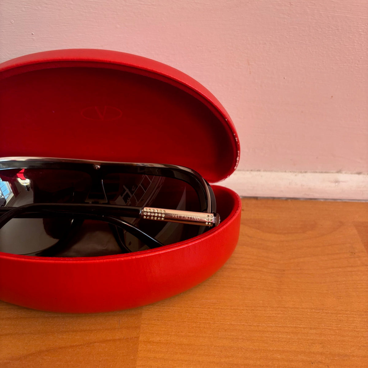 Valentino black sunglasses with rhinestone detailing and red hard case featuring logo.