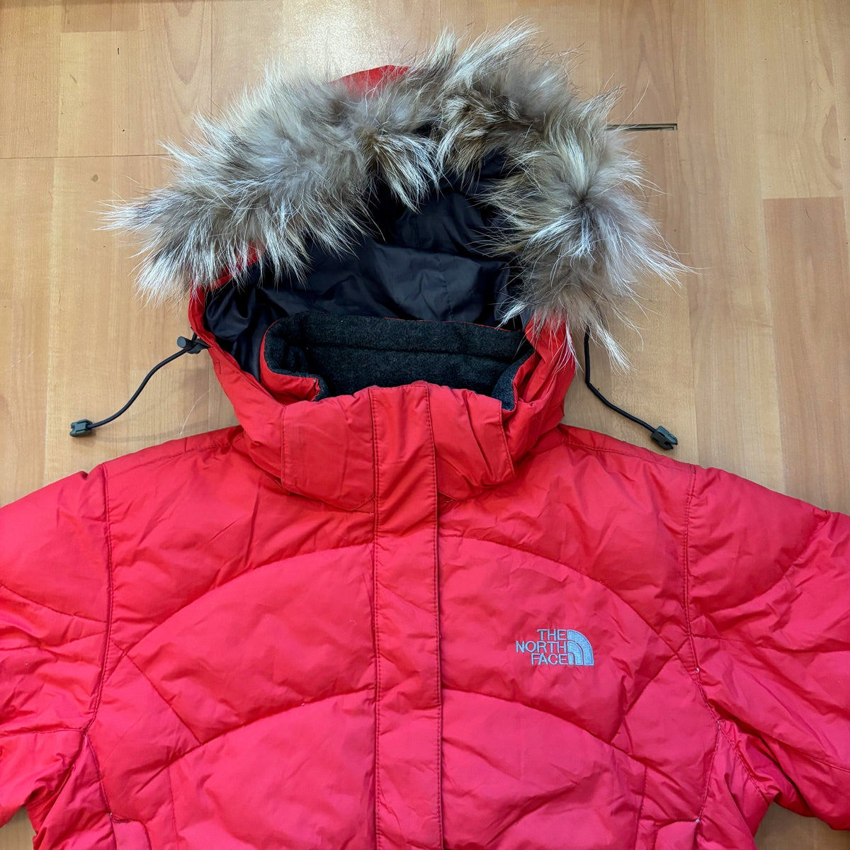 The North Face red down jacket with faux fur hood, ribbed cuffs, and zip pockets.