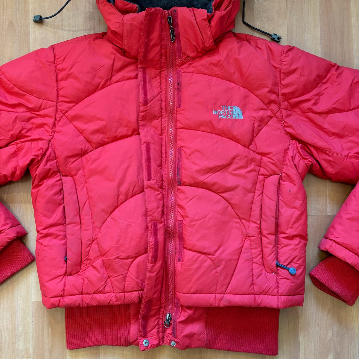 The North Face red down jacket with faux fur hood, ribbed cuffs, and zip pockets.