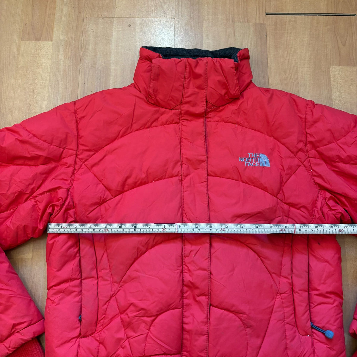 The North Face red down jacket with faux fur hood, ribbed cuffs, and zip pockets.