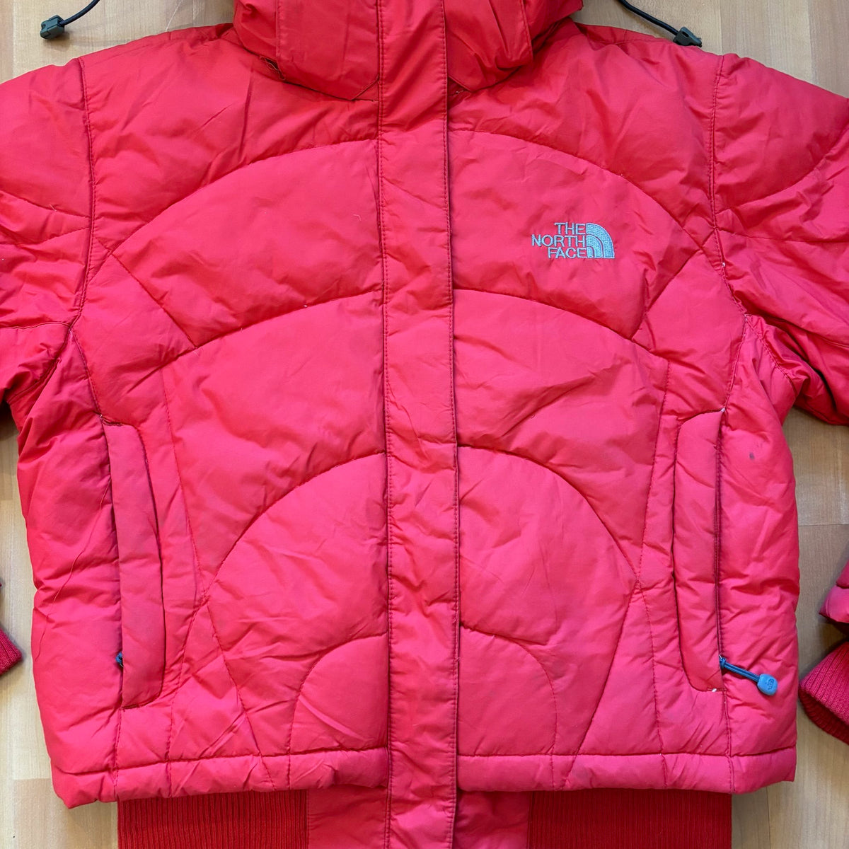 The North Face red down jacket with faux fur hood, ribbed cuffs, and zip pockets.