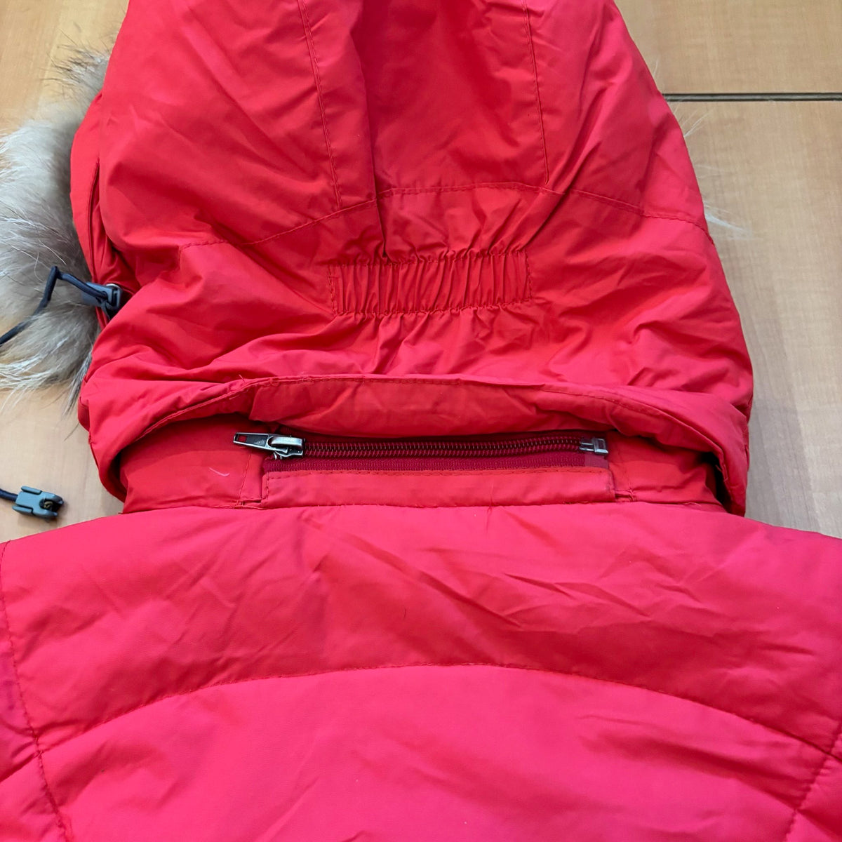 The North Face red down jacket with faux fur hood, ribbed cuffs, and zip pockets.