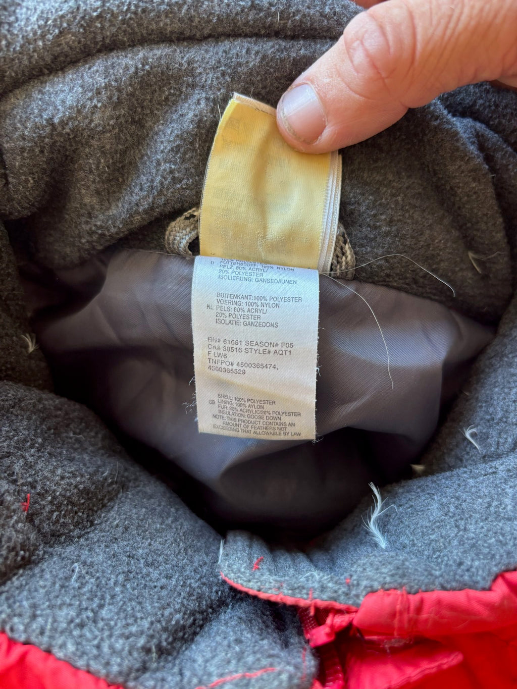 The North Face red down jacket with faux fur hood, ribbed cuffs, and zip pockets.