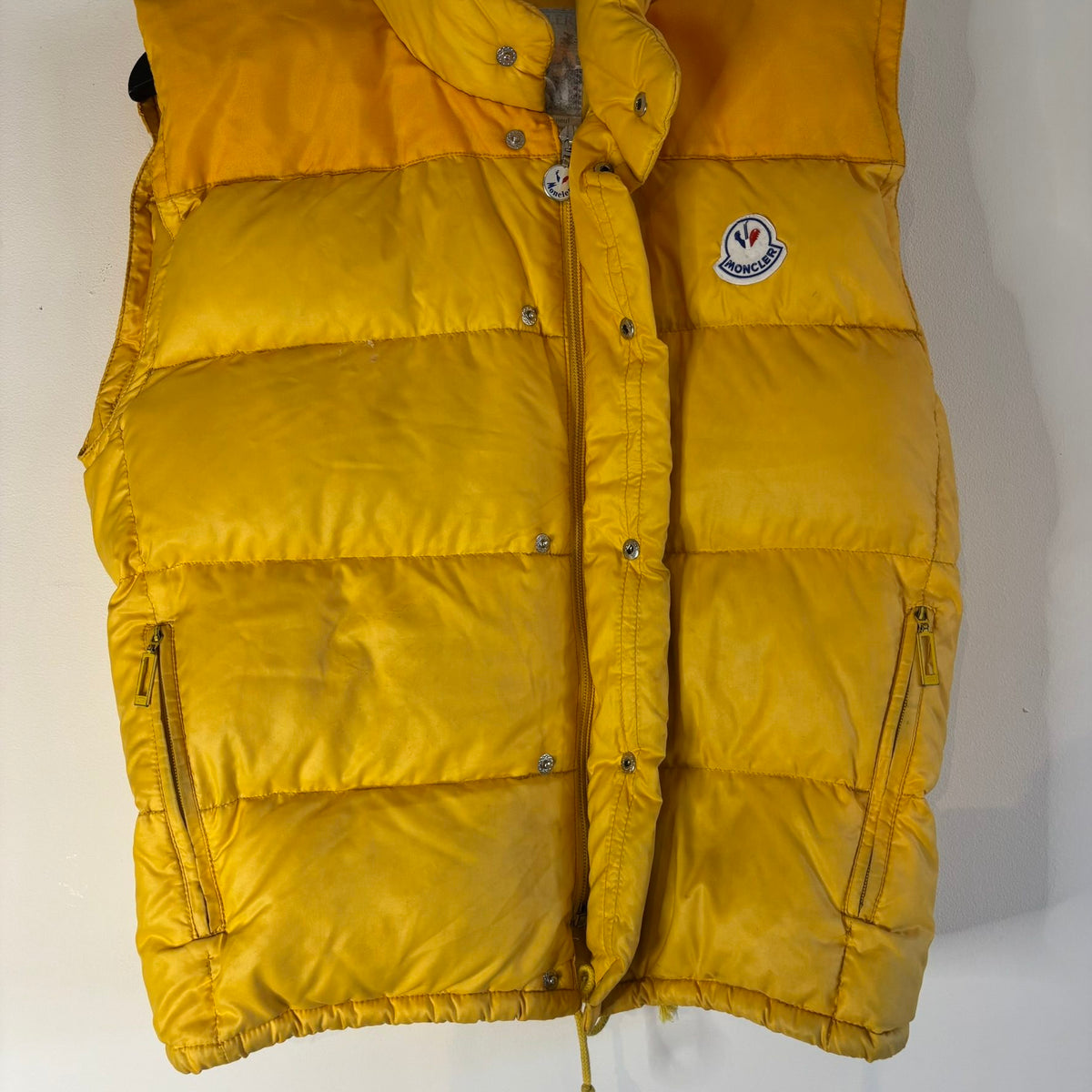 Moncler yellow down gilet vest with snap-button placket and zip pockets, made in France.