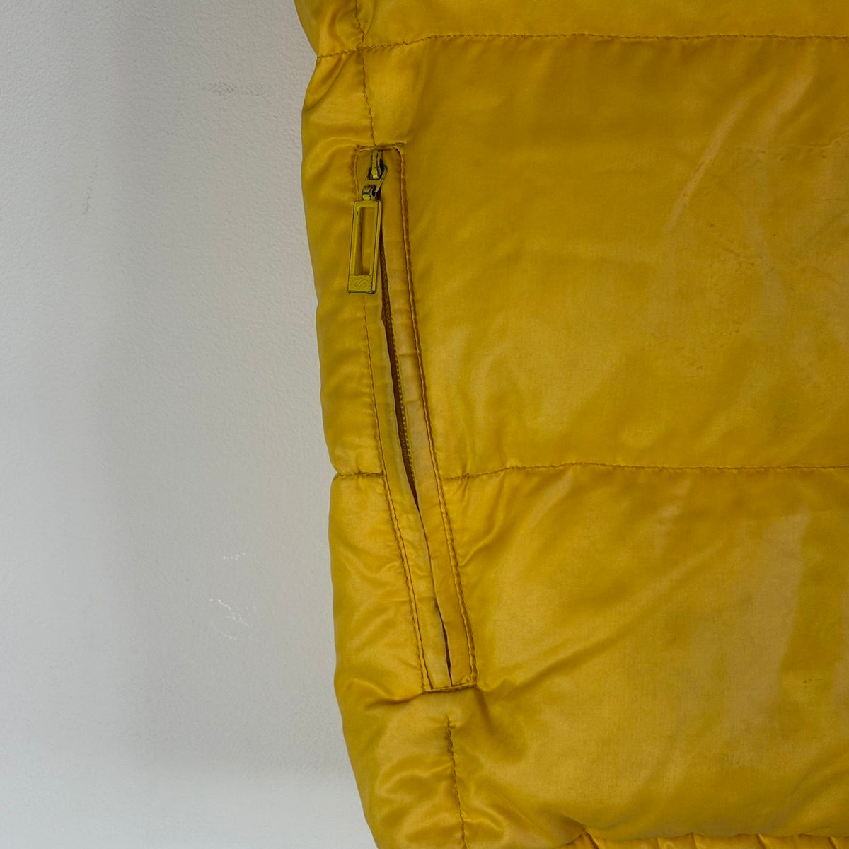Moncler yellow down gilet vest with snap-button placket and zip pockets, made in France.