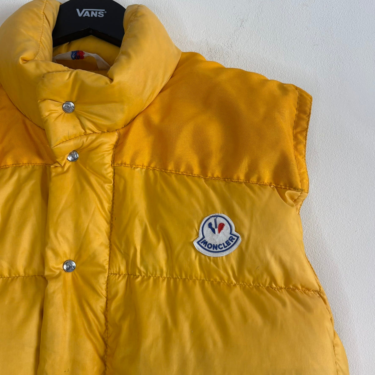 Moncler yellow down gilet vest with snap-button placket and zip pockets, made in France.