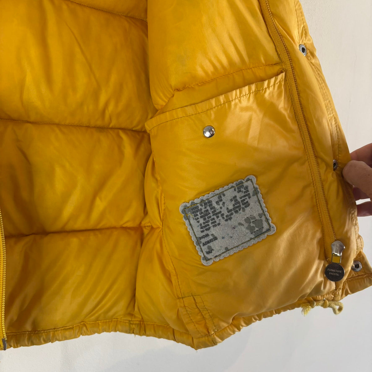 Moncler yellow down gilet vest with snap-button placket and zip pockets, made in France.