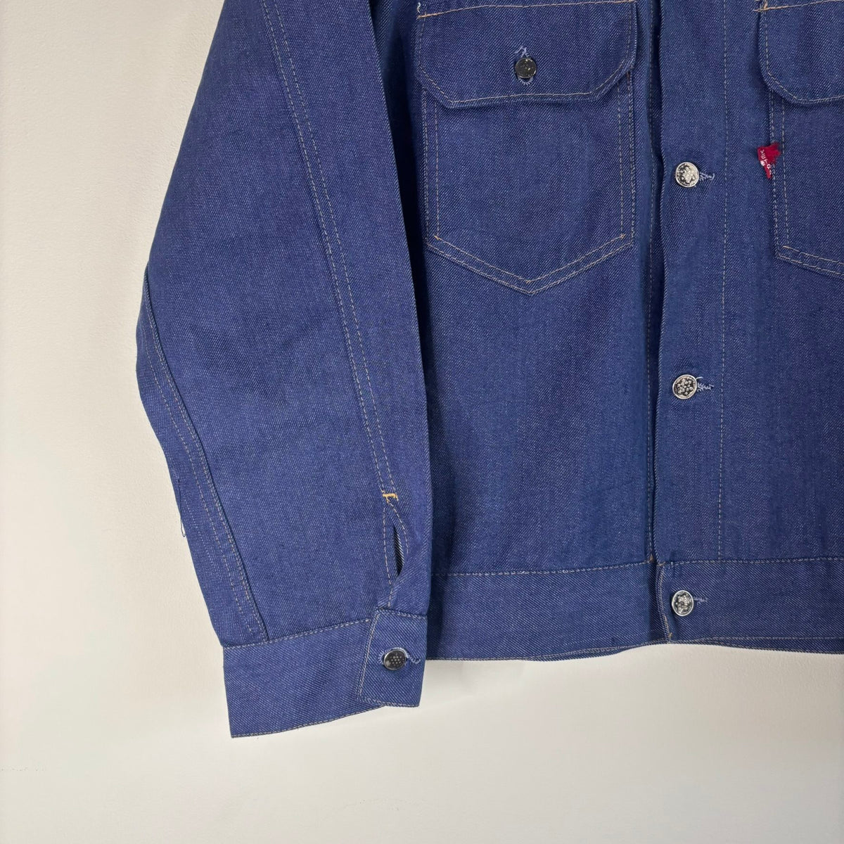 Vétra blue denim jacket with gold stitching, star-embossed buttons, and red logo tab.