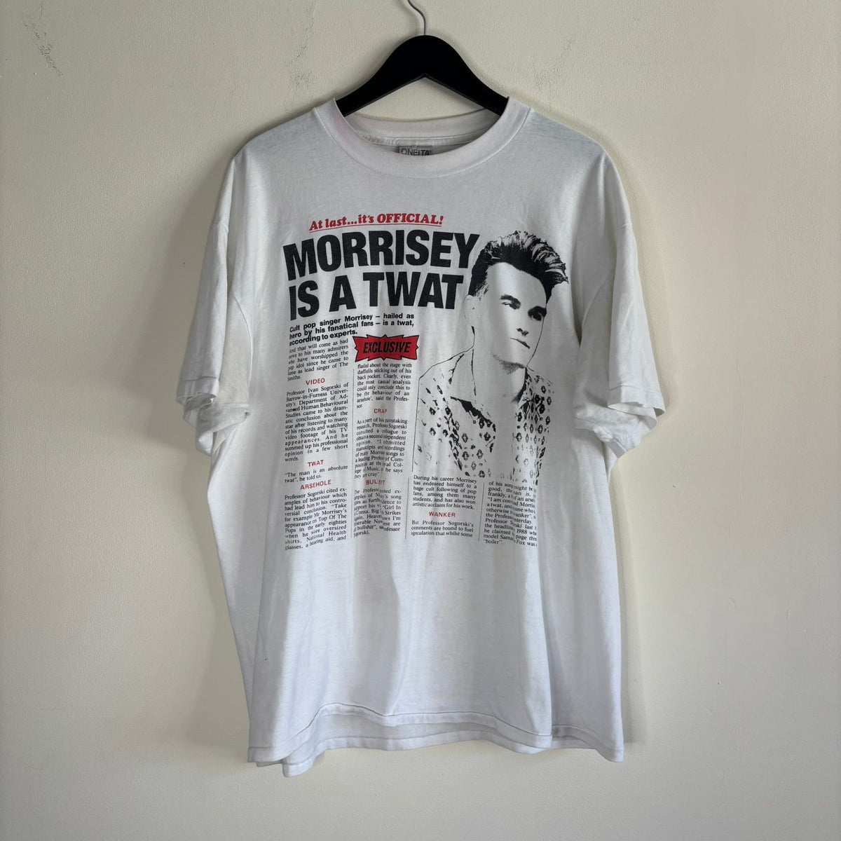 Oneita black graphic tee featuring Morrissey tabloid print and red "EXCLUSIVE" flash.